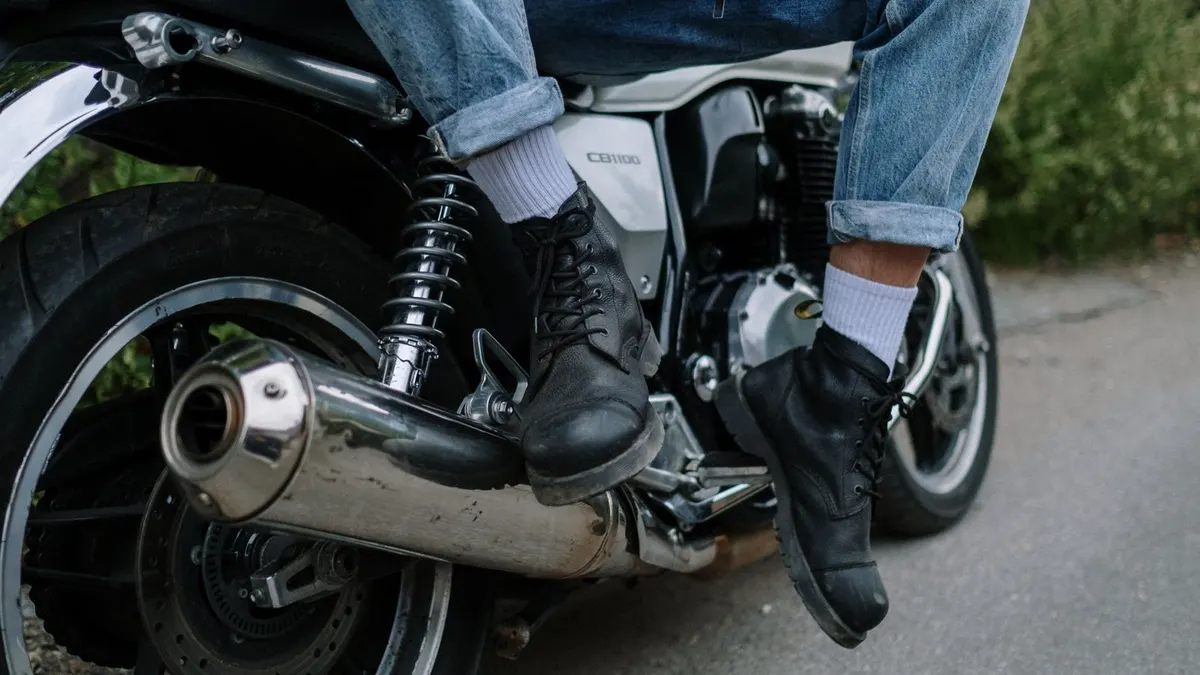 Paire de bottes moto touring en cuir noir posée sur un marchepied, gros plan sur les renforts et fermeture.