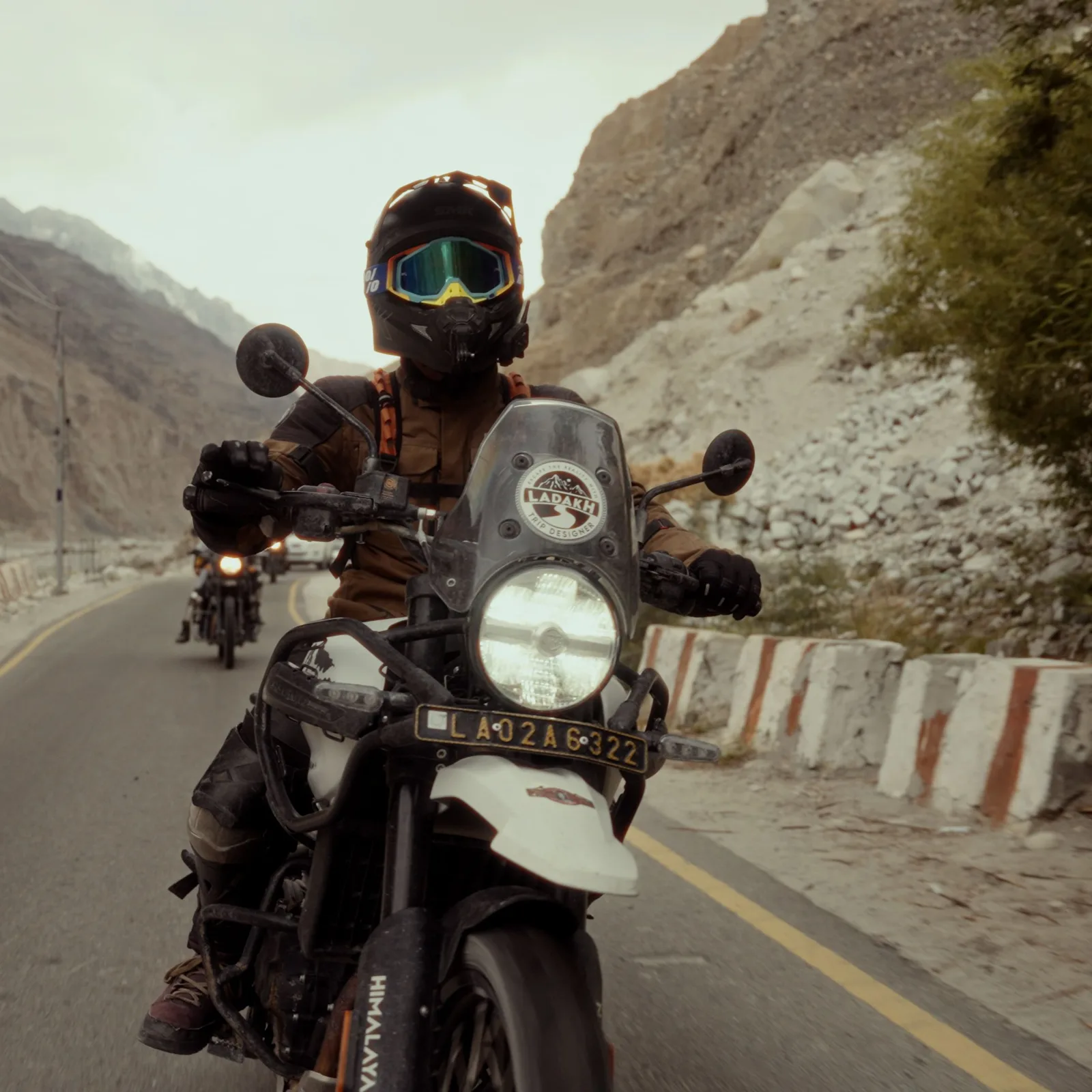 Motard en virage sur une route de col, montagnes en arrière-plan