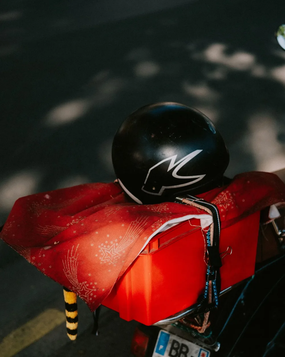 Moto rouge garée en plein soleil, casque posé sur le guidon